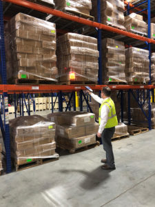 WDS Savannah uses state of the art warehouse management software. Here, an employee is scanning a wrapped pallet of goods on racking.